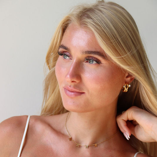 Smuk kvinde med guldøreringe i naturligt lys – stylinginspiration til hverdagslook